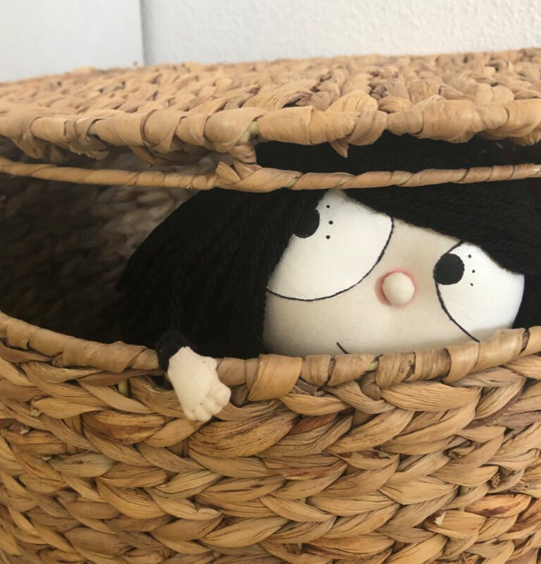 Muñeca de Lítera asomando de una cesta de mimbre